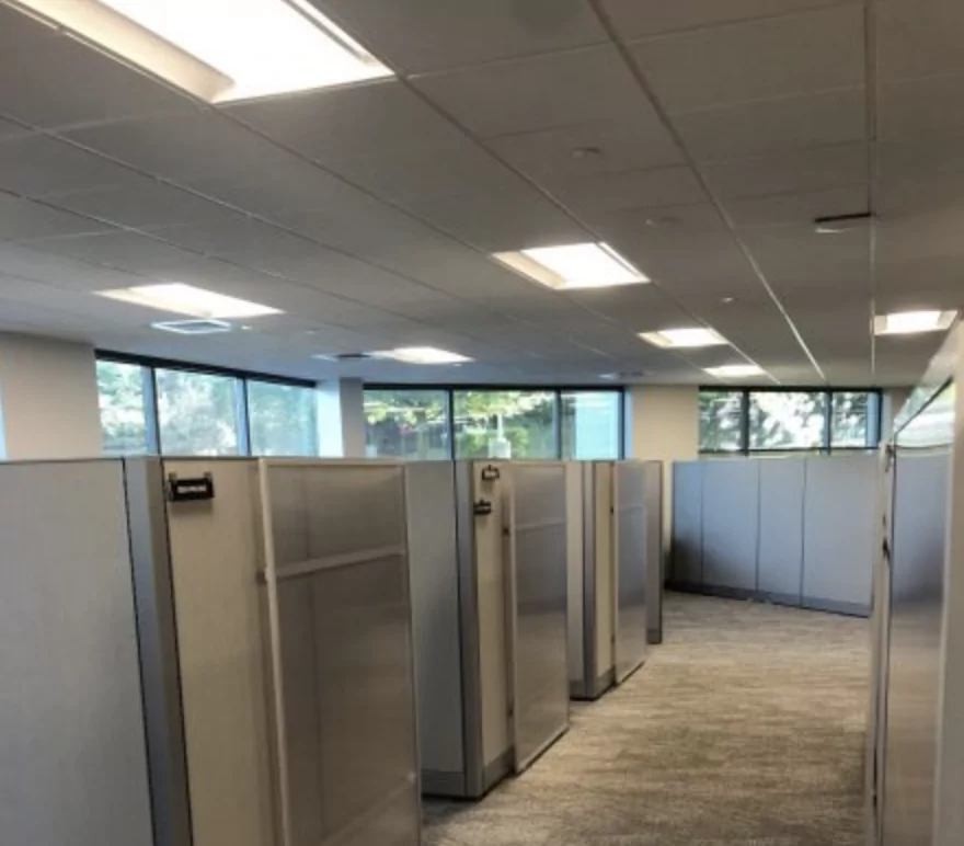 Office interior featuring cubicles and large windows, designed for workspace efficiency, highlighting the modern office environment associated with Furniture Soup's products.